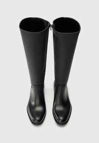 Botas de borracha pretas até ao joelho com uma textura suave, forma retangular e fecho de correr na parte de trás. Design minimalista com um bico arredondado.