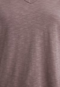 V-Ausschnitt T-Shirt in einem sanften Mauve-Ton, aus einem texturierten, leicht melierten Stoff. Das Design ist schlicht, ohne weitere Muster oder Akzente.