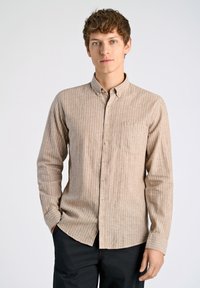 Camicia a maniche lunghe a righe beige e bianche con colletto abbottonato, tasca frontale e orlo arrotondato. Tessuto dalla superficie liscia.