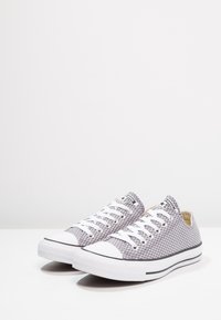 Baskets en mesh gris avec lacets blancs, embout en caoutchouc et bande noire. Dotées d'une surface texturée et d'un design bas pour un usage décontracté.