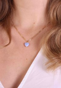 Gouden ketting met een iriserende lichtblauwe hartvormige hanger. De ketting bestaat uit ovale schakels, wat zorgt voor een gestructureerde uitstraling.