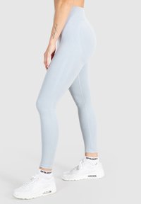 Leggings azzurro chiaro a vita alta realizzati in tessuto elasticizzato, con una texture a coste e dettagli delle cuciture. Abbinati a sneakers bianche.
