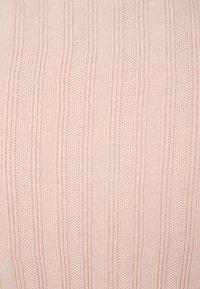Tissu tricoté beige avec des rayures verticales, présentant un motif texturé de sections alternées en relief et plates, créant une profondeur visuelle.