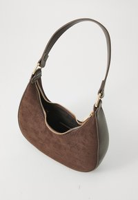 Pieni ruskea mokkainen olkalaukku, jossa on kultainen vetoketju osittain auki, tummasta nahasta valmistettu olkahihna ja sivupaneelit valkoista taustaa vasten.