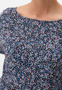 Blommigt mönstrad topp med marinblå bakgrund och små vita, rosa och blå blommor. Rundad halsringning och mjukt, strukturerat tyg.