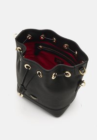 Sac en cuir noir en forme de seau avec quincaillerie dorée, fermeture à cordon et intérieur rouge avec une poche zippée pour l'organisation.