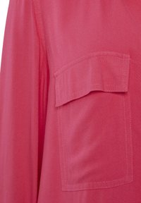 Pink shirt with a smooth texture, featuring a chest pocket and visible stitching details. The fabric appears lightweight and breathable.