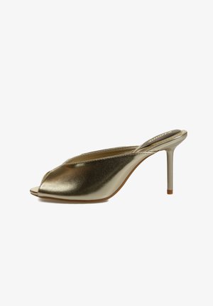 Mule dorado metálico con puntera abierta, tacón alto de aguja y diseño sin cordones.