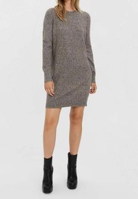 Robe-pull en maille dans un mélange gris moucheté, avec manches longues, col rond et coupe ajustée, associée à des bottes à plateforme noires.