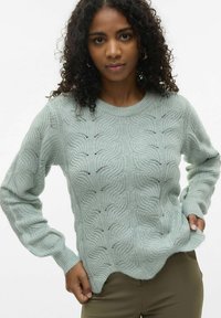 Ljust grönt stickat tröja med en vågig m�önster, ribbad halsringning och muddar, samt en något scalloped nederkant. Texturerat, medelviktigt tyg.