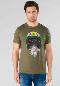 Camiseta de manga corta color verde oliva con un estampado gráfico de un casco con gafas de sol y un paisaje urbano, fabricada en una mezcla de algodón.