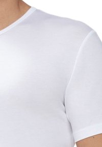 T-shirt en coton blanc à manches courtes avec un col rond, texture lisse et design ajusté, mettant en valeur les détails des épaules et des manches.