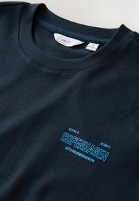 Mørkeblå crew-neck t-shirt lavet af bomuld, med blå tekst der står "KØBENHAVN" med koordinater og "STORKØBENHAVN" nedenunder.