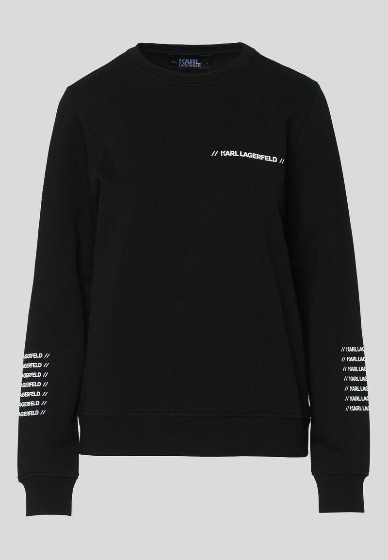 Sweat-shirt noir en tissu doux, avec manches longues, encolure ronde et logo blanc imprimé sur la poitrine et les manches.
