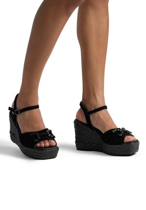 Sandali con zeppa neri in suede, con cinturini alla caviglia, design open-toe, abbelliti con paillettes, dotati di suola piattaforma intrecciata e texture.