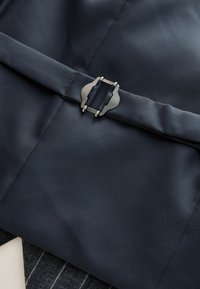 Navy fabric featuring a smooth texture with a metallic clasp closure detail. The design includes a horizontal belt-like accent.
