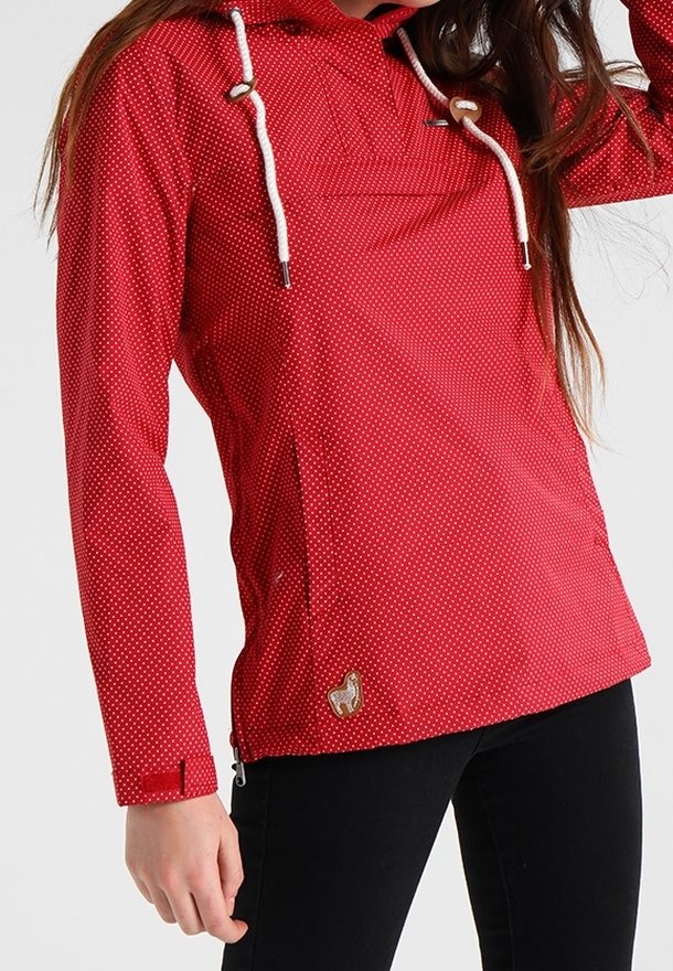 Red waterproof jacket with white polka dots, adjustable hood, and drawstrings. Features zippered side pockets and a small logo accent.