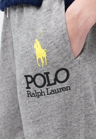 Szürke pamut melegítőnadrág sárga pólójátékos logóval és fekete "POLO Ralph Lauren" felirattal az oldalsó zseben. Puha tapintású.