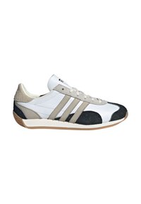 Scarpa atletica bianca con una punta nera testurizzata, accenti grigi e tre strisce grigie. Presenta una parte superiore in pelle liscia e una suola in gomma.