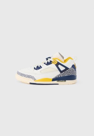 Weißer Sneaker mit gelben und dunkelblauen Akzenten, Mesh-Panel und grauen Elefanten-Print-Details entlang der Sohle und Ferse.