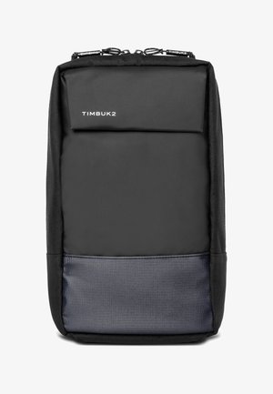 Schwarzer Nylon-Rucksack mit einer glatten oberen Fläche und einem strukturierten grauen unteren Bereich. Verfügt über ein Logo und verstellbare Träger. Minimalistisches Design.