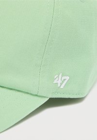 Απαλό πράσινο καπέλο από υφασμάτινη υφή, με λευκό κεντημένο λογότυπο "47" στο πλάι. Κ αμπύλη γείσο και δομημένος σχεδιασμός.