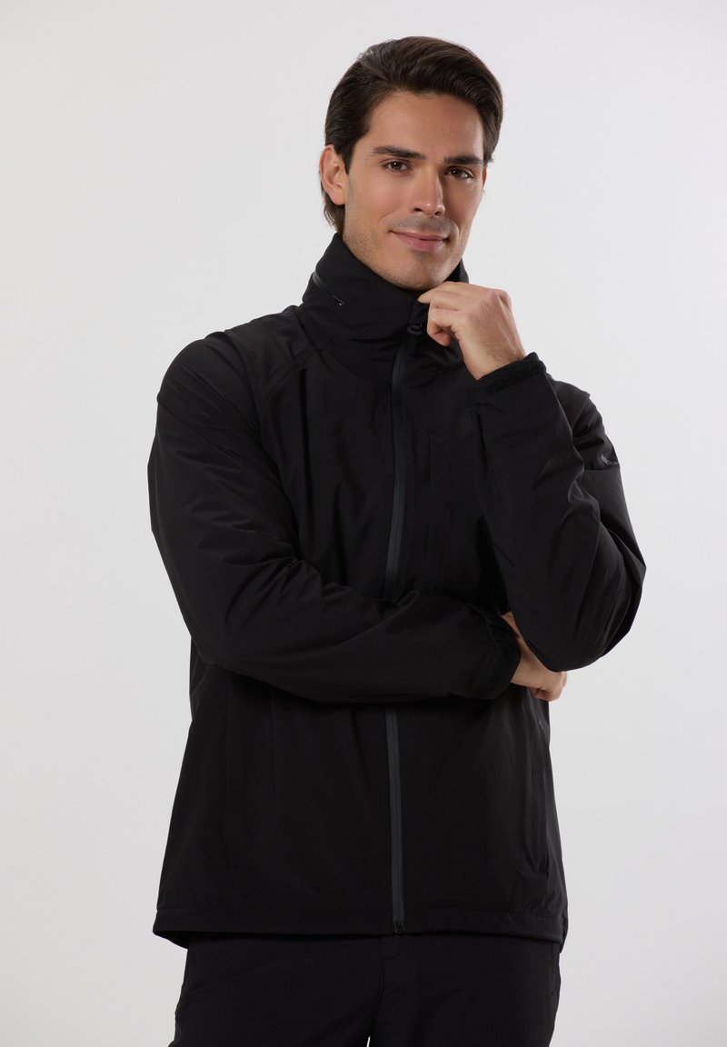 Černá zateplená bunda s vysokým límcem a zipovým zapínáním. Má hladkou tkaninu, dlouhé rukávy a jemné švy.
