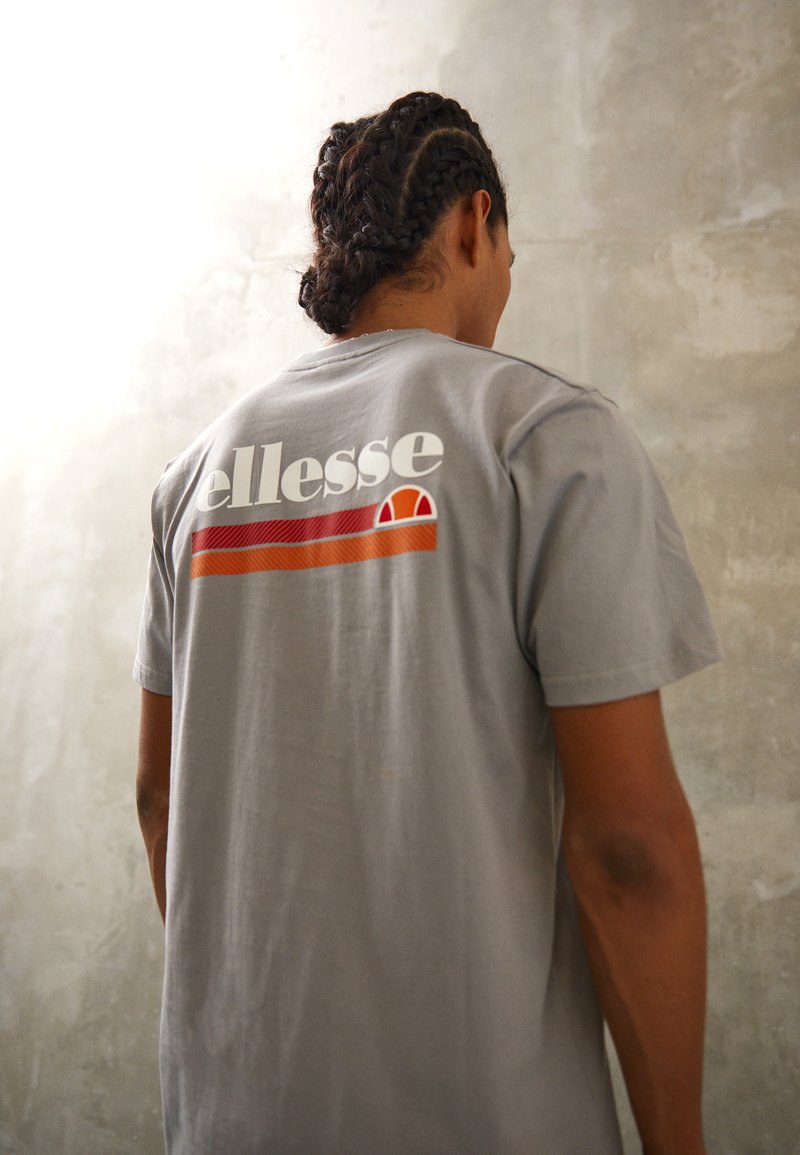 Gray cotton t-shirt featuring a colorful logo print on the back with red, orange, and white accents. Short sleeves and relaxed fit.