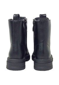 Un paio di stivali neri in pelle alla caviglia con suole spesse e linguette posteriori, mostrati da dietro su uno sfondo bianco.