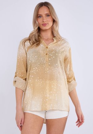 Camicia dorata chiara con motivo a stelle, tessuto morbido, apertura con bottoni, maniche arrotolabili e vestibilità comoda. L'orlo è più lungo sul retro.