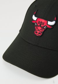 Cappellino nero con visiera curva, caratterizzato da un logo di toro ricamato in rosso sul davanti. Il materiale sembra essere tessuto intrecciato con una finitura testurizzata.