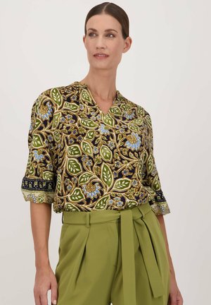 Bloes met bloemenprint en korte mouwen, met groene, blauwe en gouden patronen op een donkere achtergrond; v-halslijn en gedetailleerde manchetten.