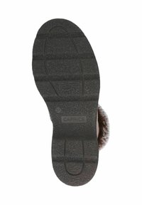 Suela de goma negra con agarre texturizado, que presenta líneas horizontales y verticales. Marca "Caprice" y tamaño "37" grabados en la suela.