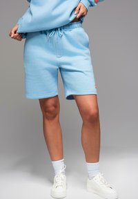 Světle modré sportovní šortky vyrobené z měkké bavlněné směsi, s elastickým pasem na šňůrku, bočními kapsami a logem.