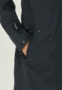 Donkerblauwe waterdichte jas met een recht ontwerp, voorzien van knoopzakken, verstelbare manchetten en textielstof.