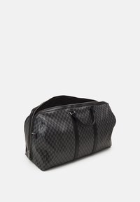 Sac de voyage noir à carreaux avec des accents en cuir lisse, de doubles poignées et une fermeture éclair. Dispose d'un intérieur spacieux et d'un design structuré.