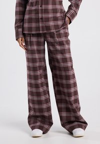 Two-piece plaid outfit in dark burgundy with white and pink accents. Loose-fitting, long sleeves, and wide-leg pants with a smooth texture.