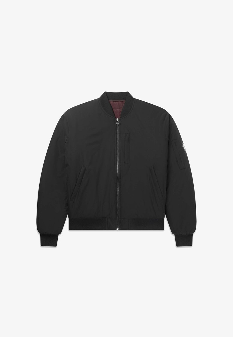 Musta bomber-takki etuvetoketjulla, kahdella sivutaskulla, resorireunuksilla hihansuissa ja helmassa sekä pienellä taskulla vasemmassa hihassa, jossa applikaatiologo.