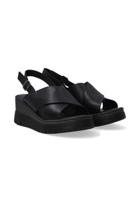 Zwarte leren wiggen-sandalen hebben een kruislings ontwerp, open teen, verstelbare enkelband en een textuurzool voor grip.
