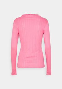 Chemise rose à manches longues en tissu côtelé avec bordure ondulée sur le col et les poignets, vue de dos sur fond blanc.