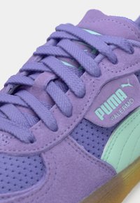 Sneaker in suede viola con sovrapposizioni in rete, dotate di dettagli in verde menta, punta rotonda, lacci spessi e suola in gomma testurizzata. Branding Puma visibile.