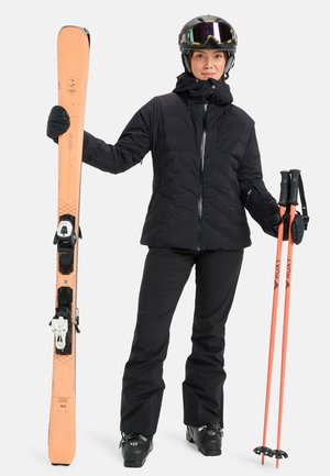 Ski set includes orange skis with black bindings, black puffer jacket, black pants, and orange ski poles with black grips. Glossy helmet and goggles.