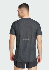 Camiseta atlética para hombre de color gris oscuro con un patrón texturizado, mangas cortas y una franja reflectante en la parte posterior.