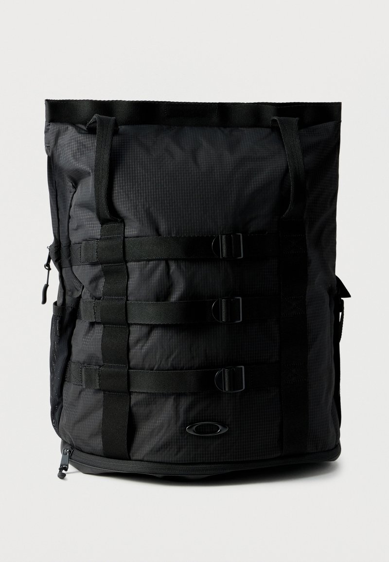 Μαύρο ορθογώνιο σακίδιο με τρεις οριζόντιες ιμάντες με αγκράφες και δύο ιμάντες ώμου, κατασκευασμένο από υφασμάτινο υλικό με υφή, με μικρό λογότυπο στο μπροστινό μέρος.