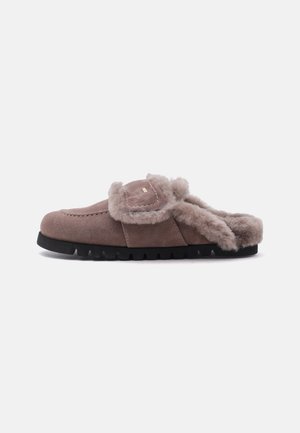 Zapatilla marrón de ante sin cierre con forro de lana suave y suela de goma negra, diseñada para la comodidad y el calor en interiores.