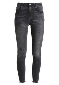 Jeans ajustados de denim negro desgastado, con un ligero detalle de desgaste en la pierna izquierda y dobladillos deshilachados. Diseño de cinco bolsillos con cierre de botón.