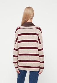 Gestreepte trui in beige met maroon en crèmekleurige horizontale strepen, met een losse pasvorm en wijde mouwen, gemaakt van zachte gebreide stof.
