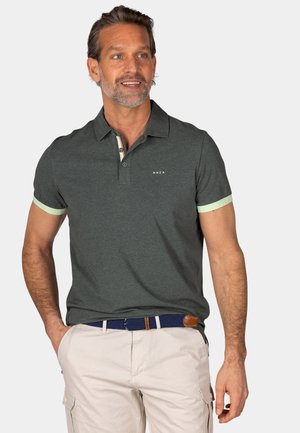 Donkergroene poloshirt met korte mouwen en lichtgroene manchetten. Beschikt over een knoopsluiting, subtiele logo en een gestreept kraagontwerp.