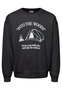 Sudadera negra de tela suave con texto blanco: "INTO THE WOODS" y gráficos de una tienda de campaña y una hoguera. Cuello redondo y puños acanalados.
