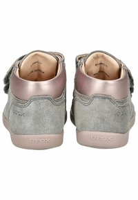 Grijze suède sneakers met een roze metallic accent op de hiel, verstelbare klittenbandsluiting en een gladde rubberen zool.